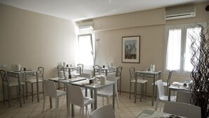 Un comedor con varias mesas y sillas, unidades de aire acondicionado y un cuadro en la pared.