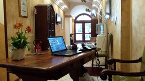 Escritorio de madera con una computadora portátil, un teléfono y una planta en un jarrón.