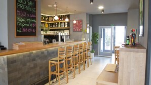 A modern bar area with a bar counter, wooden chairs, and a variety of bottles and glasses on shelves. - EA Business Hotel Jihlava (Jihlava)