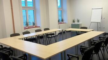 Ein Konferenzraum mit langem Tisch, Stühlen, einer Tafel und Fenstern mit Pflanzen.
