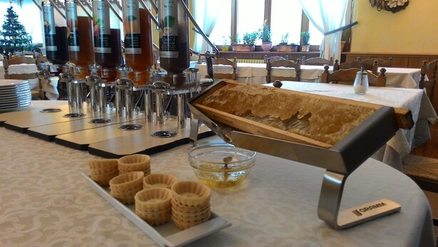 Una cafetera con varios dispensadores, una bandeja de madera con pasteles y un tazón pequeño de almíbar.