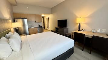 Une chambre d’hôtel comprenant un lit, un bureau, une télévision, une kitchenette et une salle de bain.