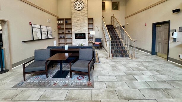A spacious lobby with a seating area, a staircase, and a fireplace. - Country Inn & Suites by Radisson, Port Charlotte, FL (Port Charlotte)