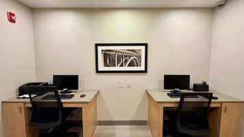 Una sala de conferencias con dos escritorios, cada uno con un ordenador, teclado y ratón. Hay un cuadro en la pared y un detector de incendios a la izquierda.