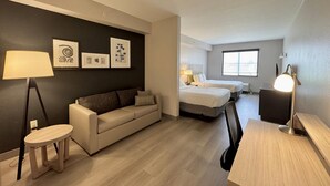 A modern hotel room with a sofa, two beds, a desk, and a small table. - Country Inn & Suites by Radisson, Port Charlotte, FL (Port Charlotte)