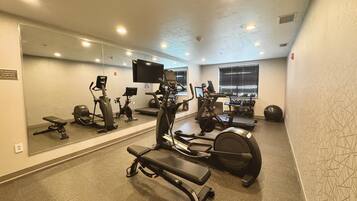Un gimnasio con diverso equipo de ejercicio, que incluye cintas de correr, bicicletas estáticas y máquinas de pesas.
