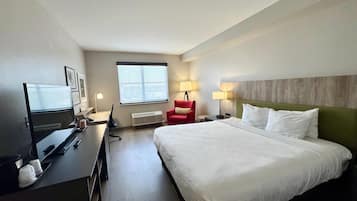 A hotel room with a bed, desk, chair, and a television.