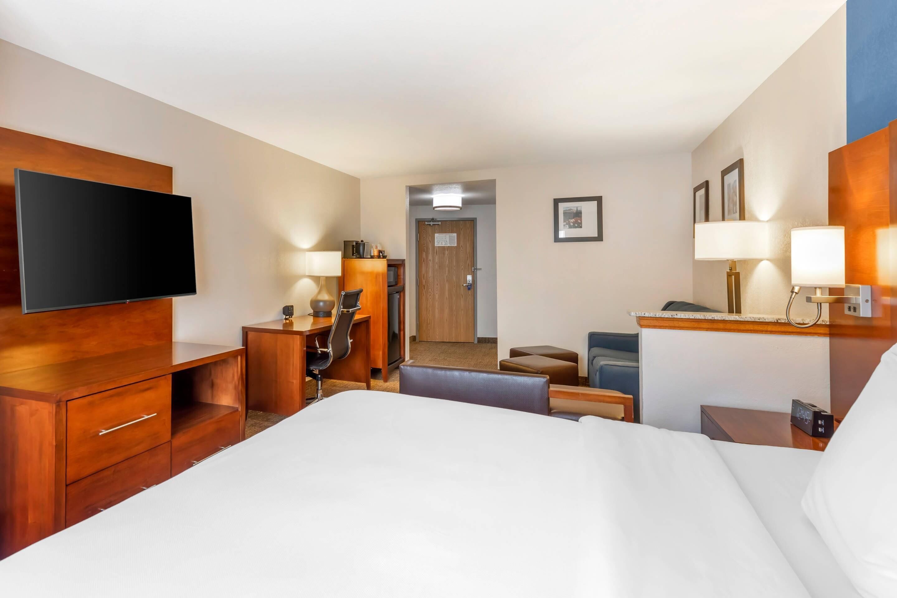 Ein Hotelzimmer mit einem Bett, einem Schreibtisch, einem Stuhl, einem Fernseher und einer Schreibtischlampe.