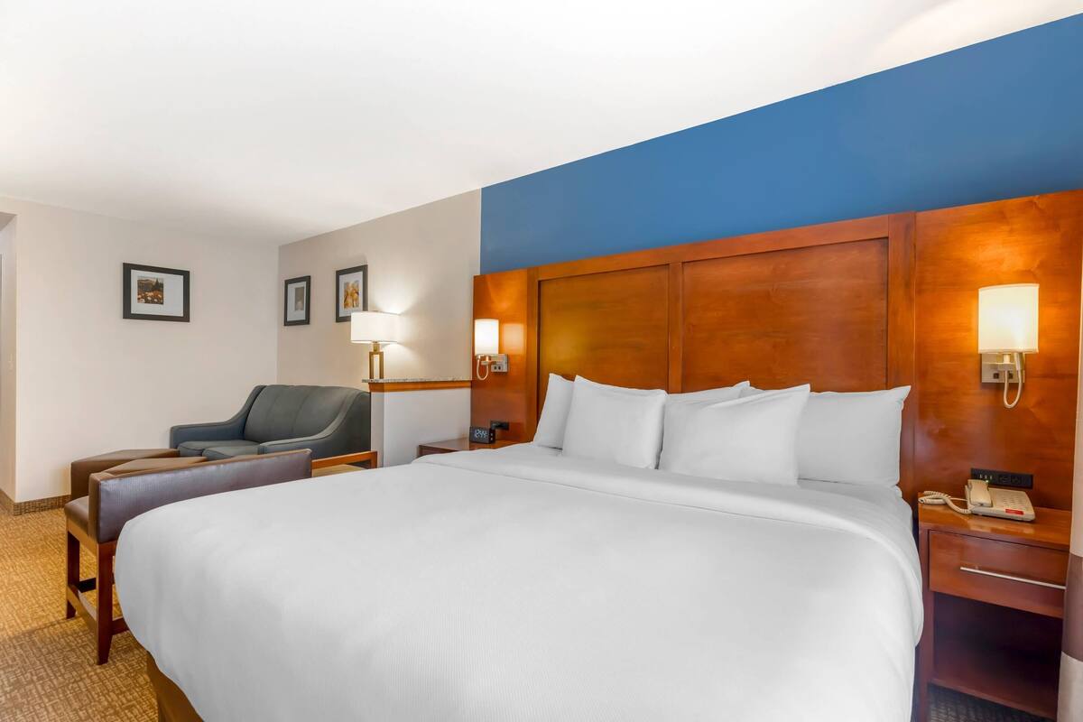 Una habitación de hotel con una cama grande, un escritorio con teléfono, una silla y una lámpara.