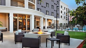 A hotel courtyard with outdoor seating, a fire pit, and a pool area. - Courtyard By Marriott Stuart (Stuart)