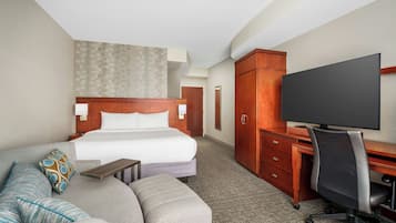 Habitación de hotel con cama, sofá, escritorio y televisor.