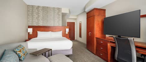 Habitación de hotel con cama, sofá, escritorio y televisor.