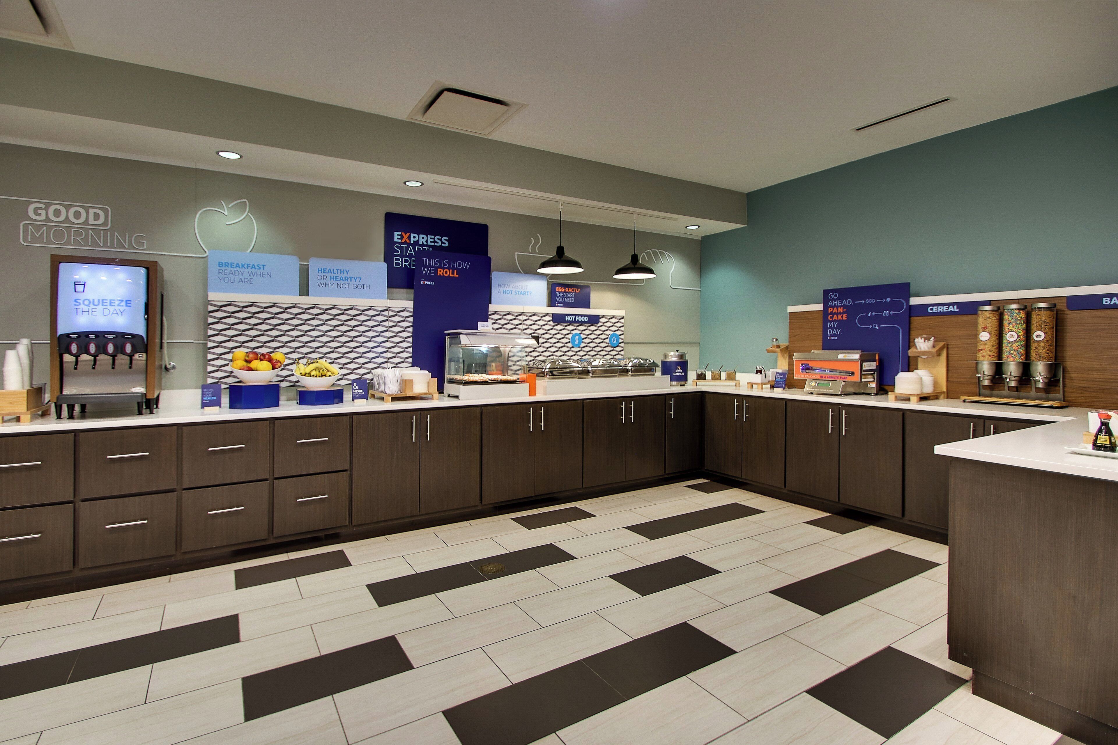 A modern breakfast area with a counter, various food items, and informational signs.