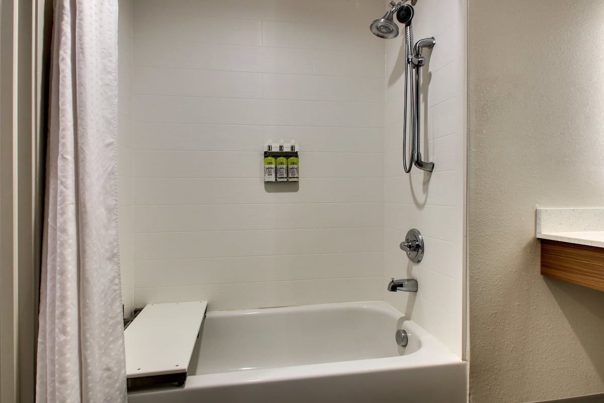 Ein Badezimmer mit Badewanne, Dusche und Ablage für Pflegeprodukte.
