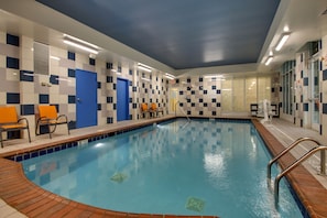 An indoor swimming pool with checkered walls, a blue door, and orange chairs. - Holiday Inn Express Lexington North-Georgetown by IHG (Georgetown)