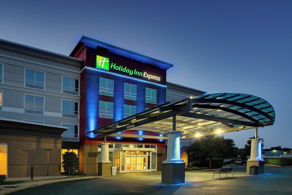 Edificio de Holiday Inn Express con entrada cubierta y cielo despejado.