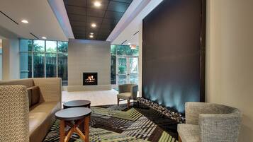 A modern lounge area with a fireplace, seating, and a view of the outdoors.