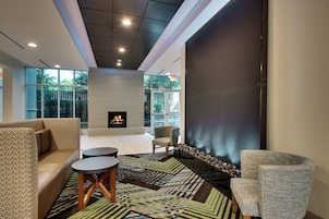 Un espacio lounge moderno con chimenea, asientos y vistas al exterior.