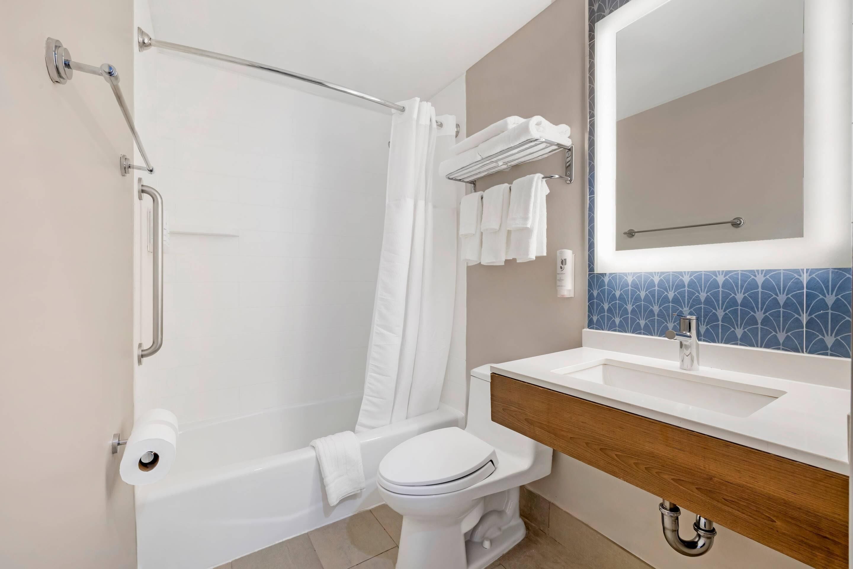 A modern bathroom with a bathtub, toilet, and vanity.