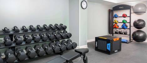 A gym with dumbbells, a bench, and exercise balls.