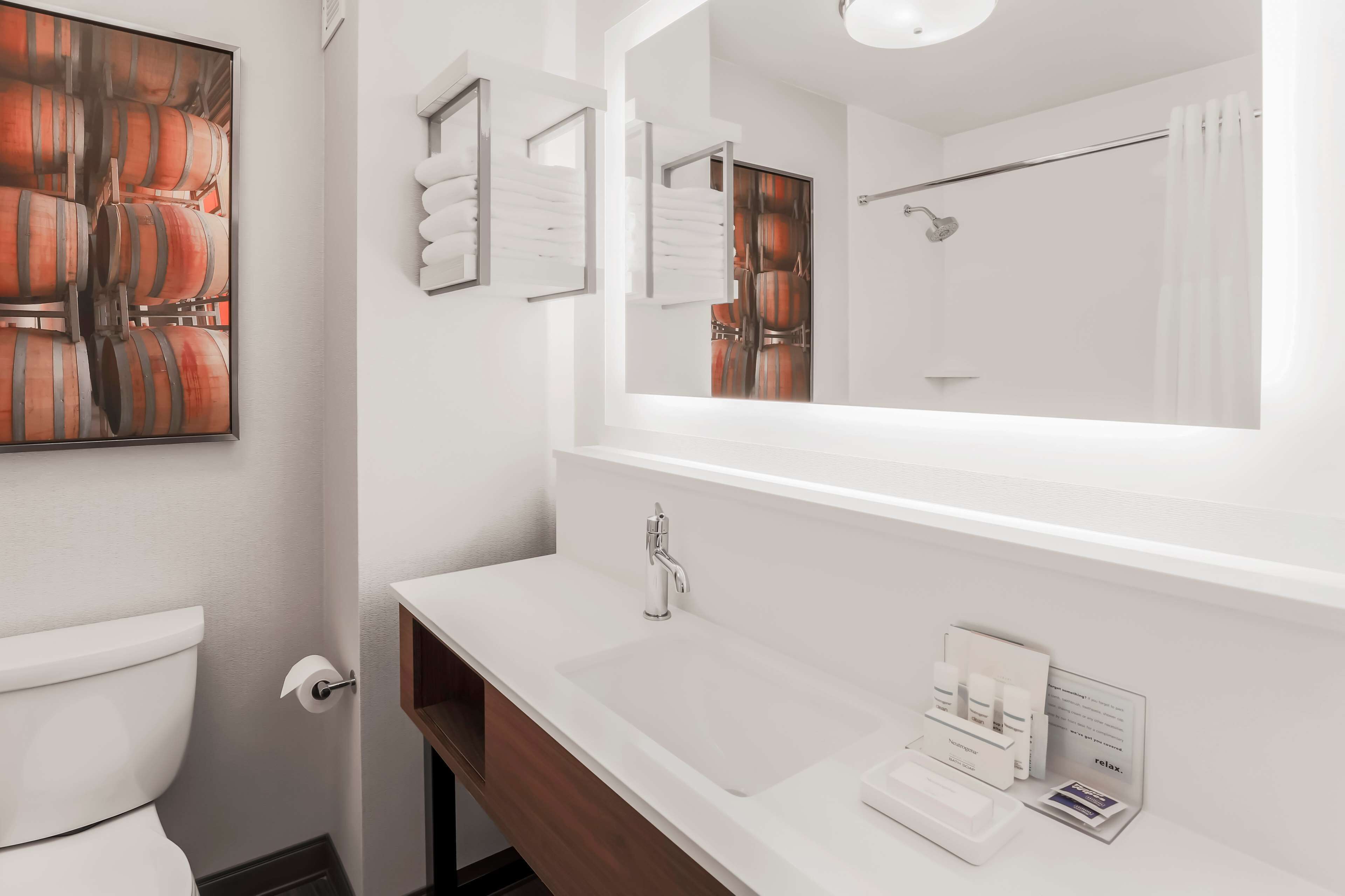 Un baño moderno con un espejo grande, lavamanos blanco y un inodoro.