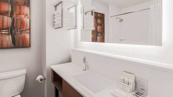 Un baño moderno con un espejo grande, lavamanos blanco y un inodoro.