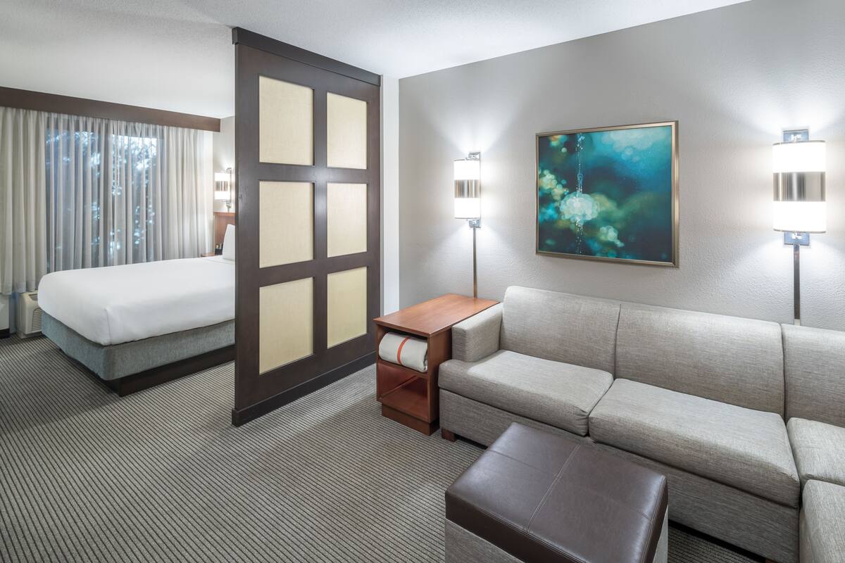 Ein Hotelzimmer mit einem Bett, einer Couch, einem kleinen Tisch und zwei Wandleuchten.