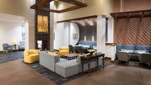 Una hall moderna con zone relax, un caminetto e una parete decorata in mattoni.
