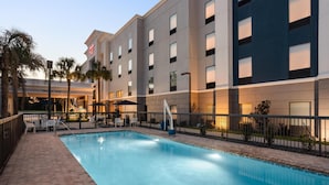 Un hotel con piscina, terraza al aire libre y cielo despejado.