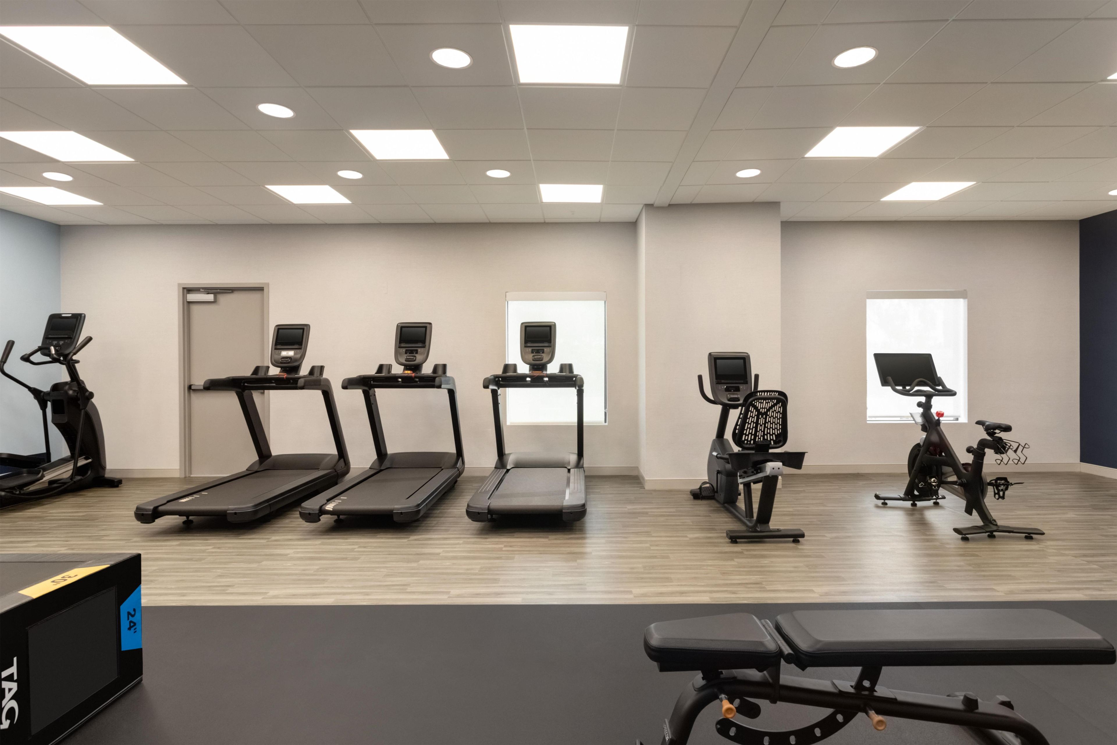 A fitness room with treadmills, stationary bikes, and a bench.