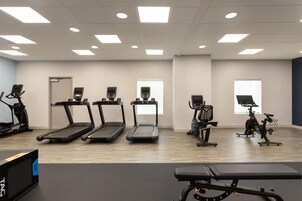 A fitness room with treadmills, stationary bikes, and a bench.