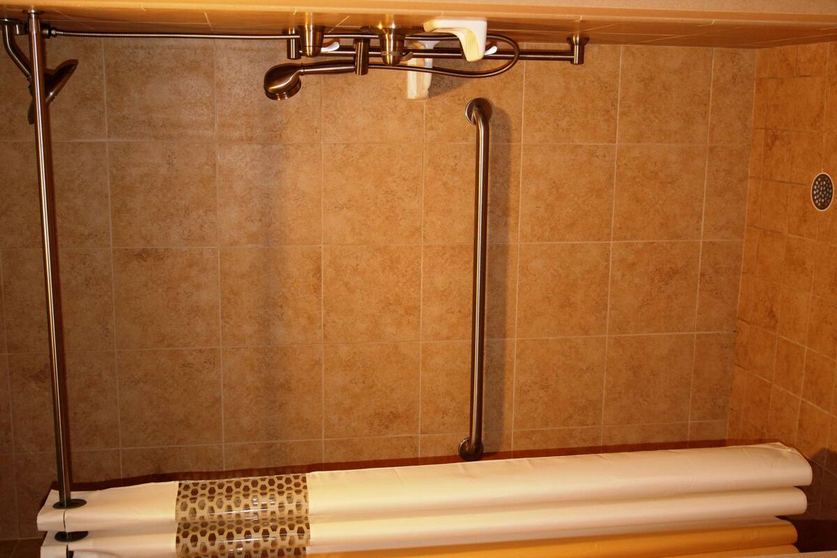 Un bagno con una vasca, un soffione e un porta asciugamani.