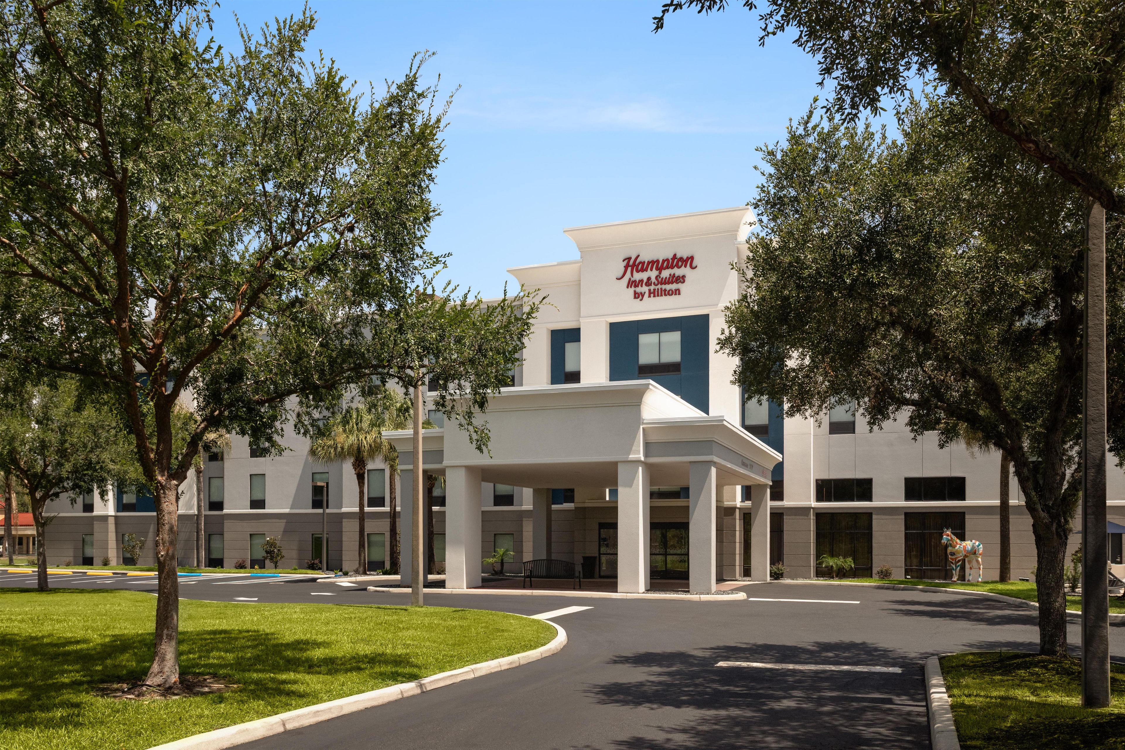 A Hampton Inn & Suites by Hilton building with a covered entrance and a parking lot.