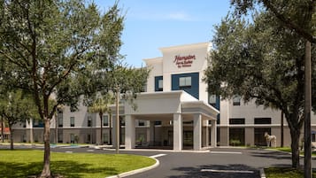 A Hampton Inn & Suites by Hilton building with a covered entrance and a parking lot.