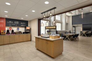 Un área de cocina moderna con una isla central, una estación de café y una zona de estar con mesa y sillas.