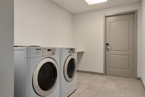 Un lavadero con dos lavadoras de carga frontal y una puerta.