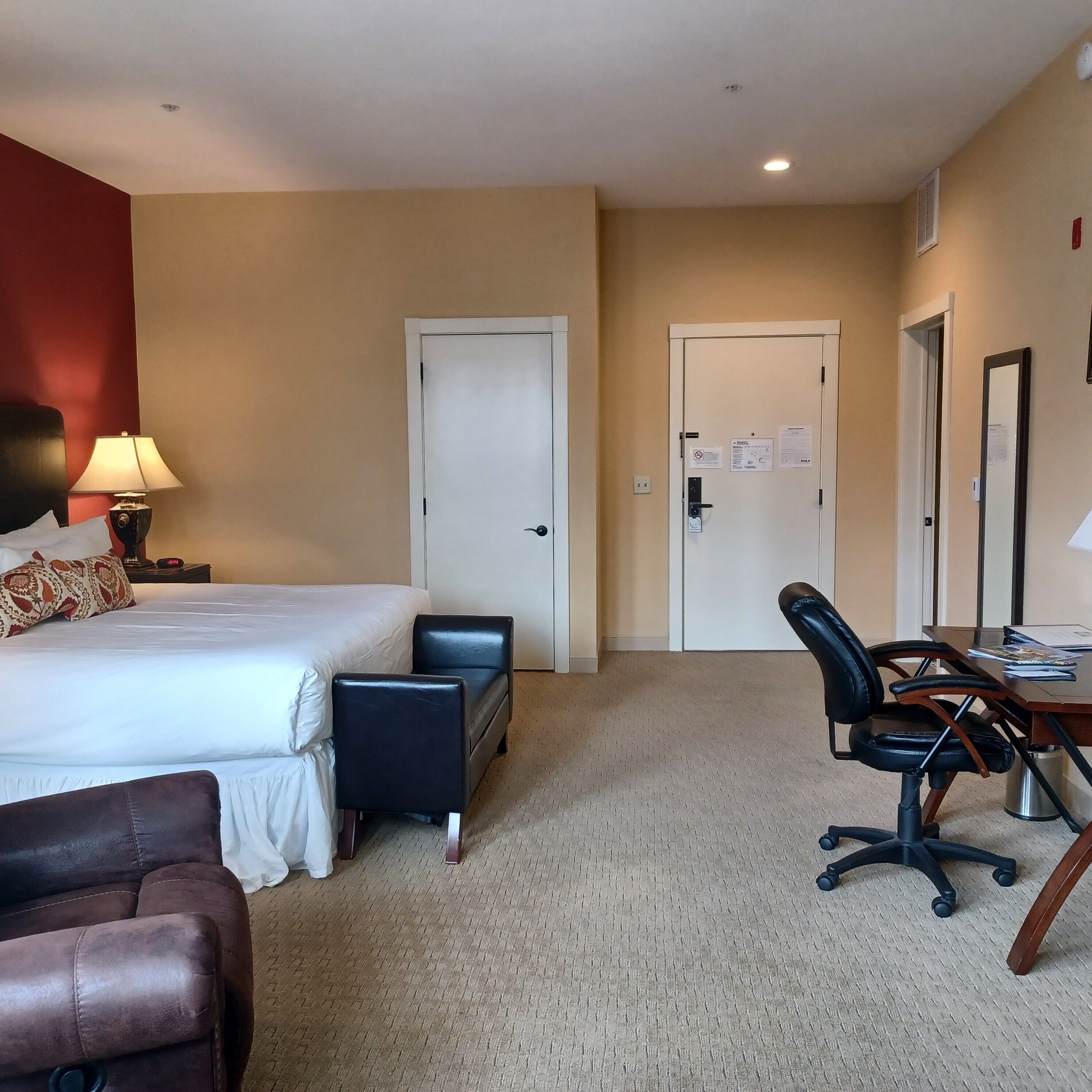 Una habitación de hotel con cama, escritorio, silla, sofá y lámpara.