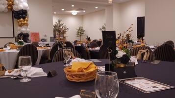A banquet hall with tables set for a formal event, featuring name cards, wine glasses, and decorative centerpieces.