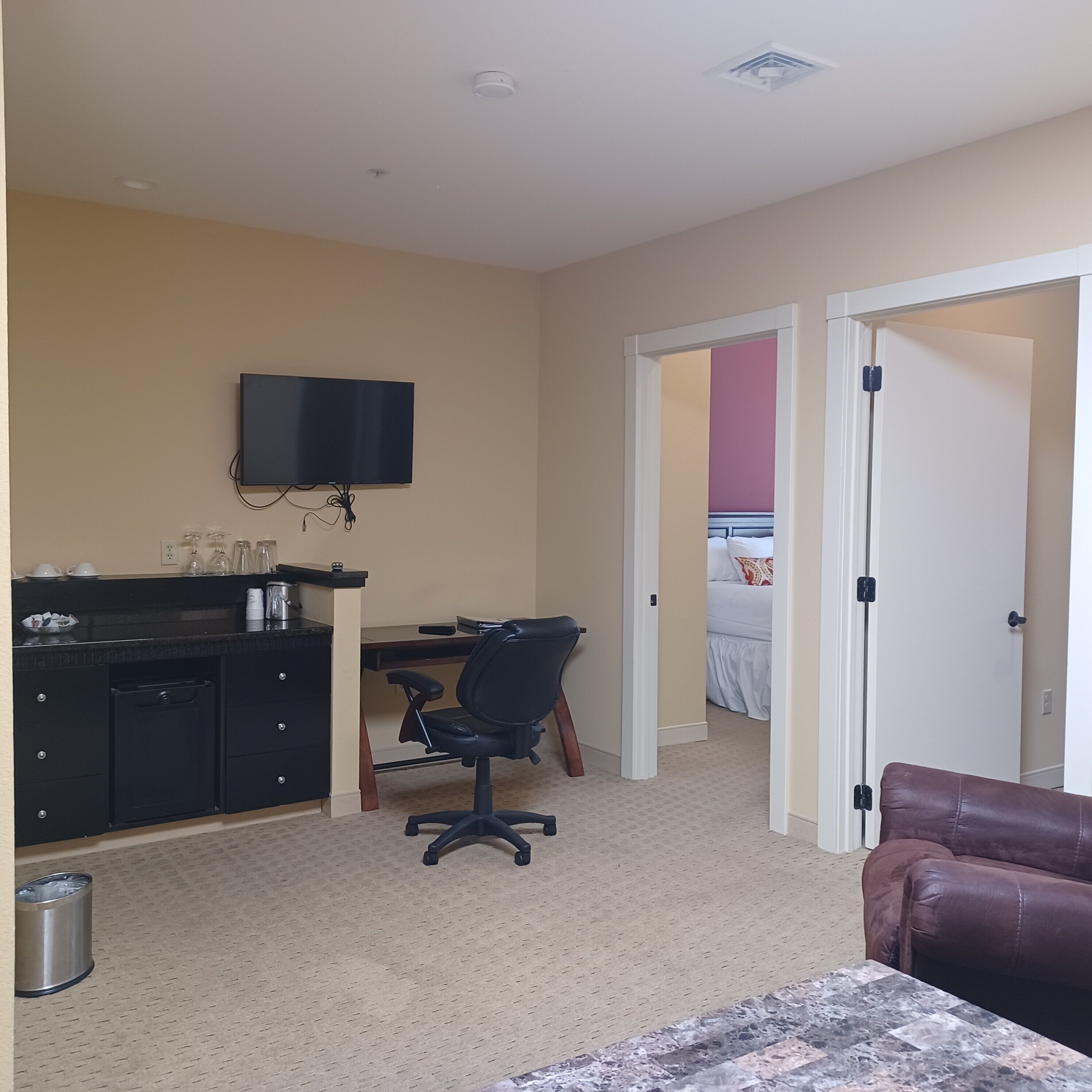 Une chambre d’hôtel équipée d’un bureau, d’une chaise, d’une télévision, d’un lit et d’un canapé en cuir marron.