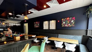 L’intérieur d’un restaurant avec des banquettes, des tables hautes et un bar.