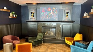 Un espace détente avec une cheminée, des fauteuils confortables et des œuvres d’art décoratives au mur.