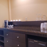 A kitchen counter with a coffee maker, cups, and glasses.