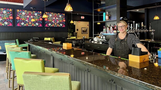 Un espace bar avec un comptoir, des tabourets de bar et des lampes suspendues.