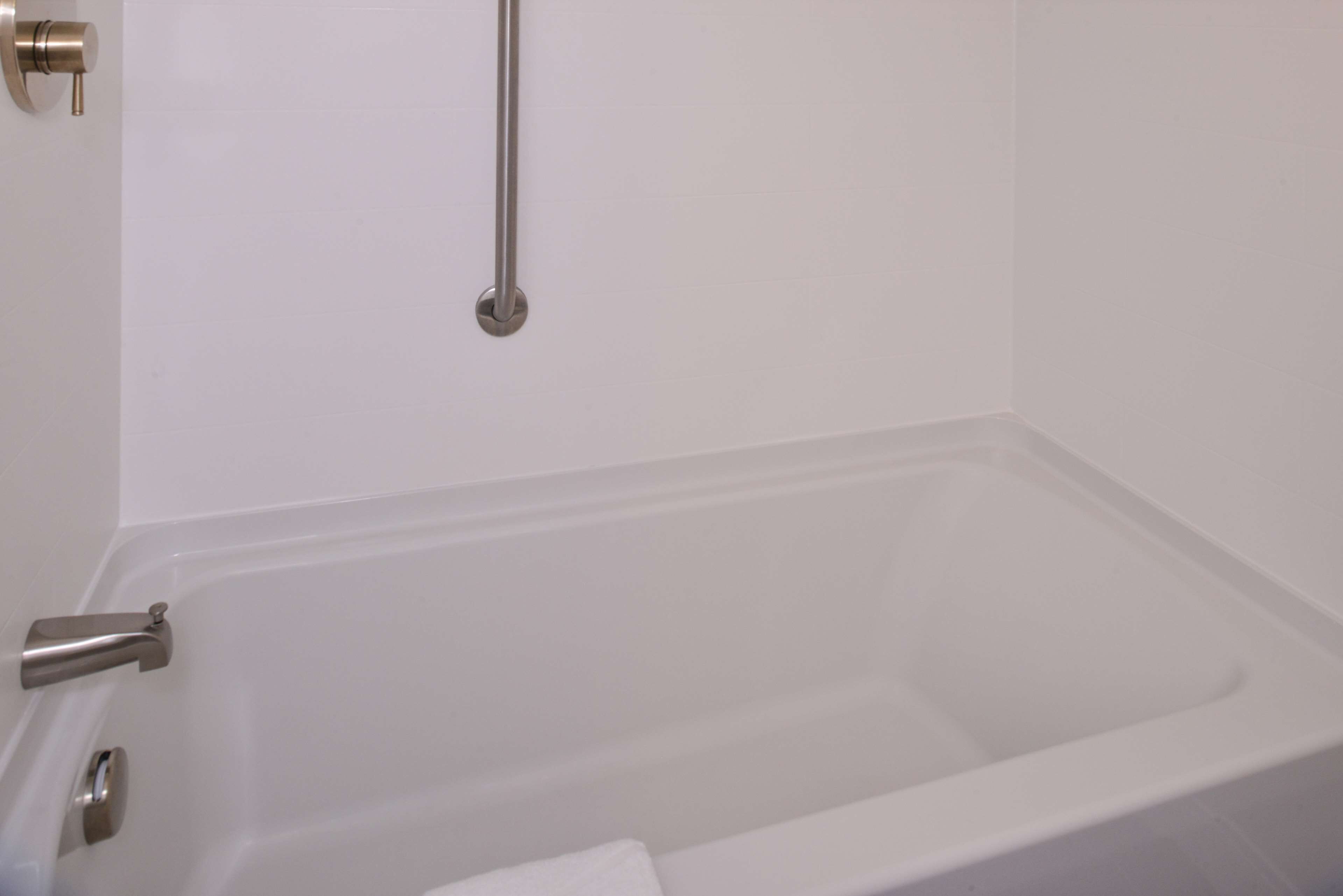 Una bañera blanca con un solo grifo y un cabezal de ducha manual.