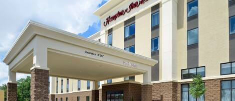 A Hampton Inn & Suites hotel with a covered entrance, clear signage, and a landscaped front area.