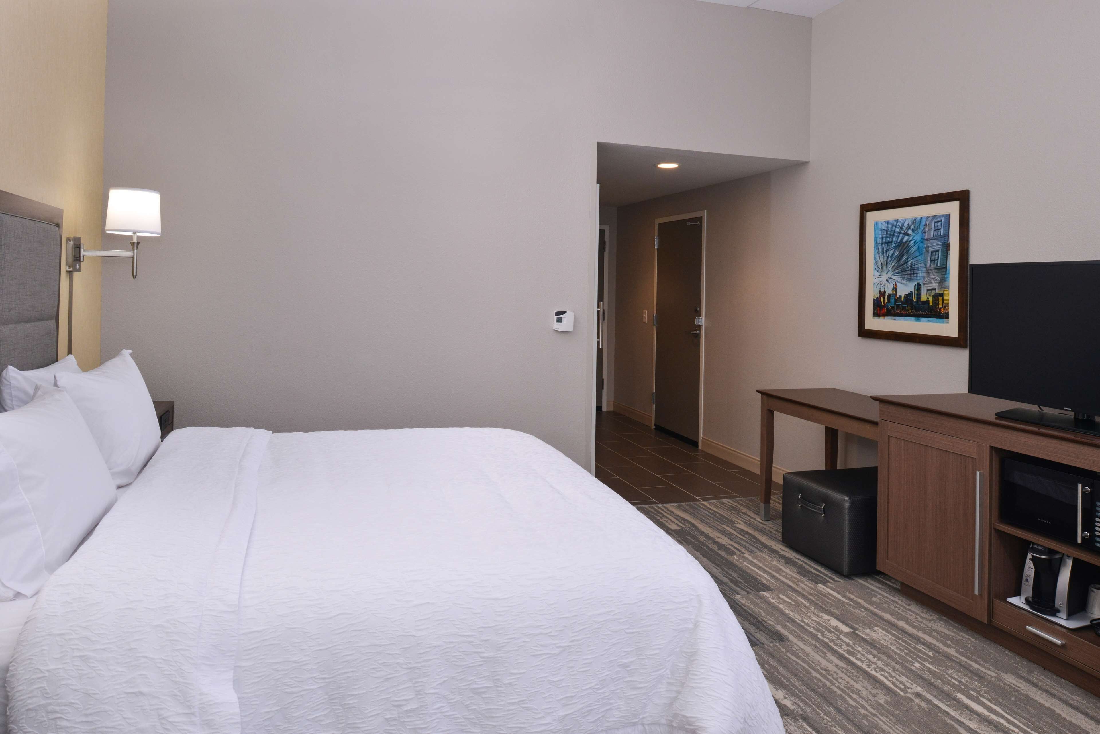 Une chambre d’hôtel avec un grand lit, un bureau, une télévision et une armoire.