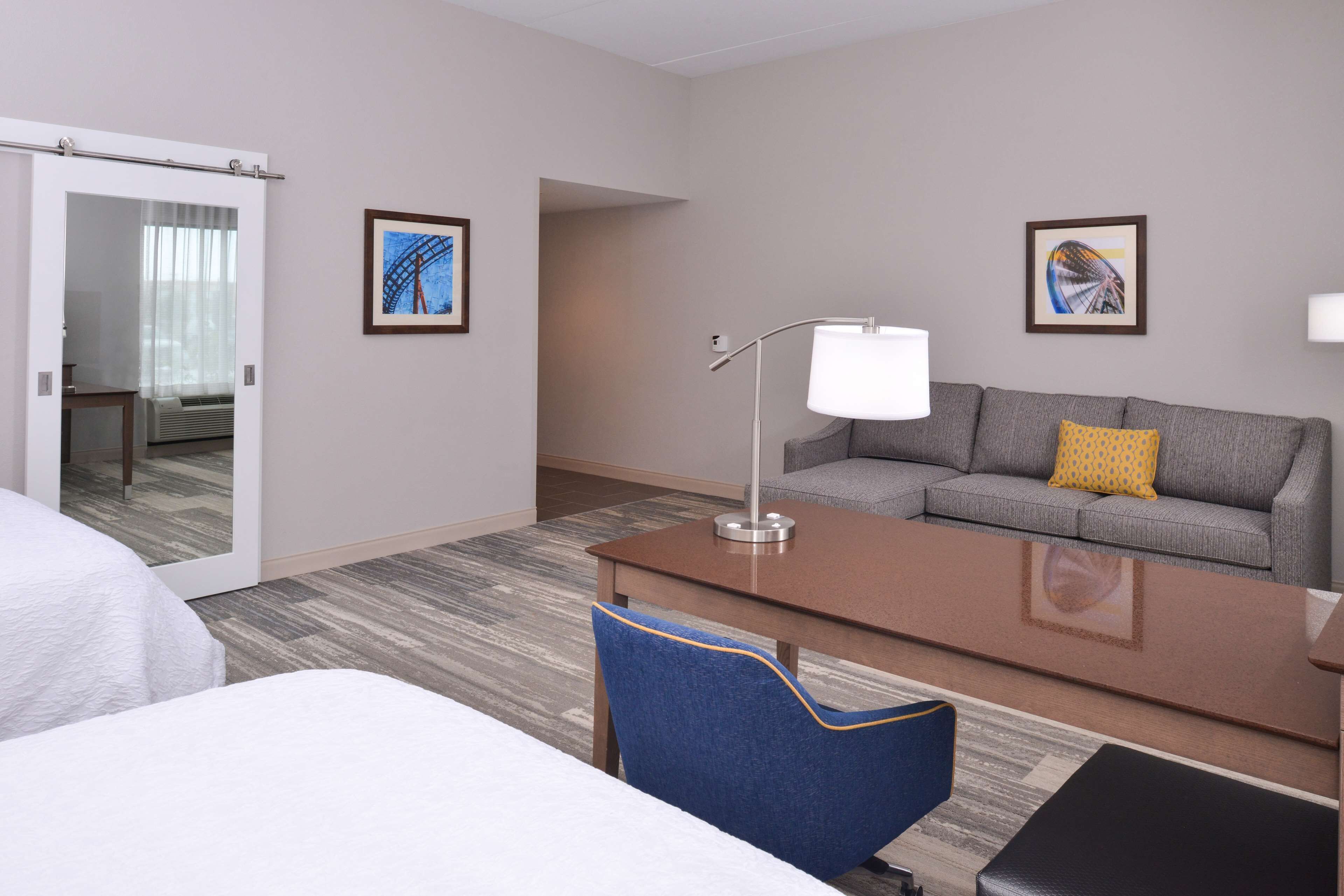 Una camera d'albergo con un letto, una scrivania, un divano e due quadri appesi alle pareti.