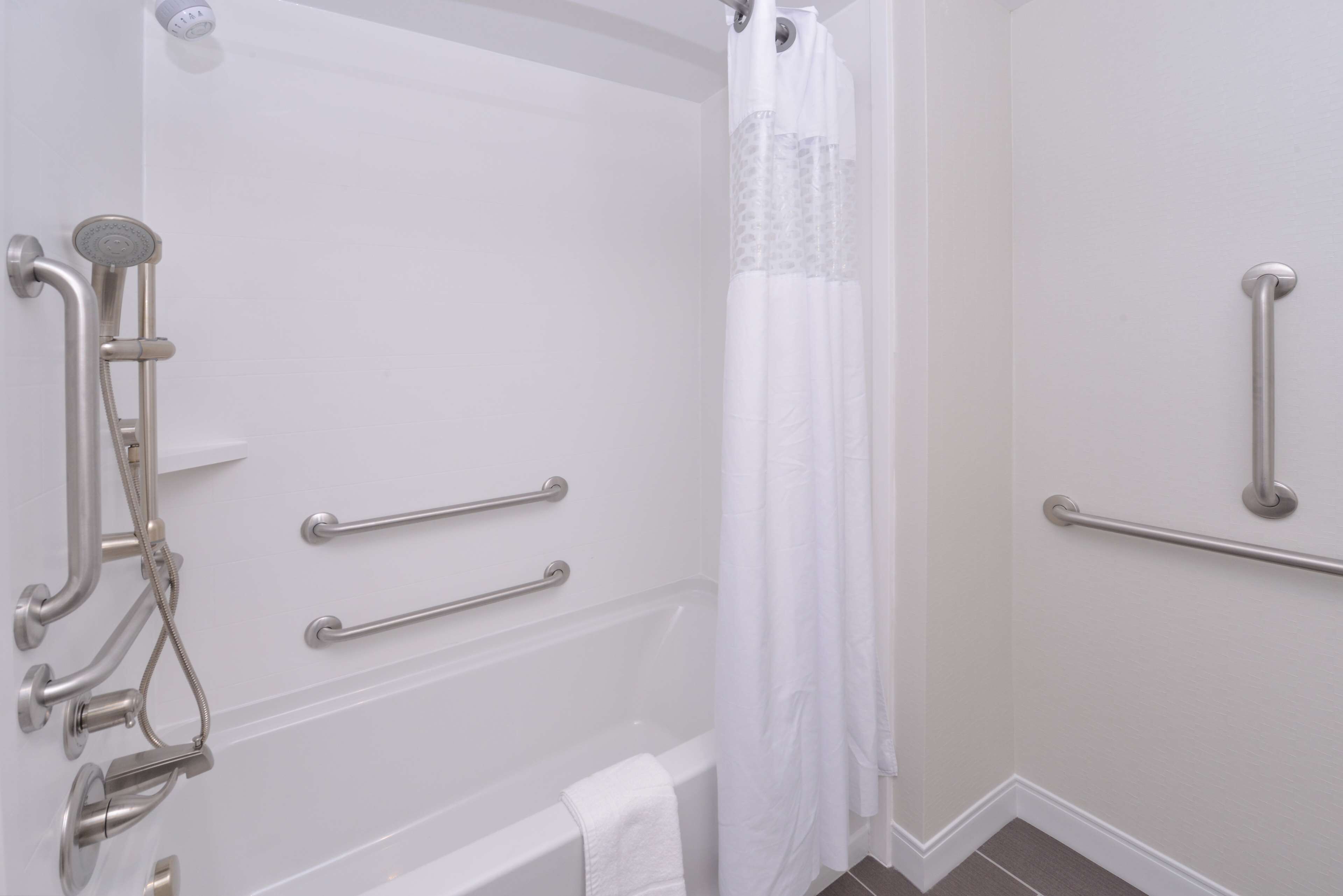 A bathroom with a bathtub, a shower, and grab bars.