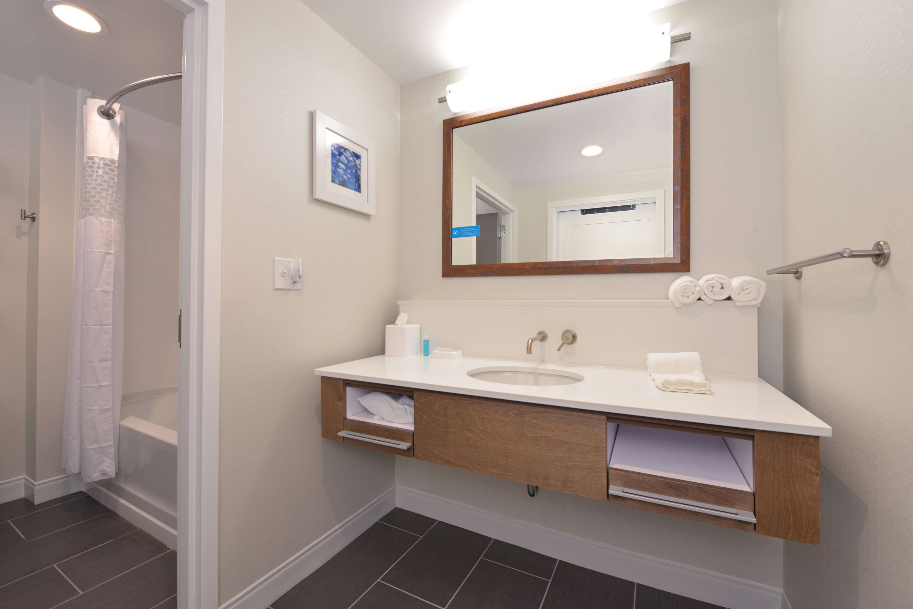A modern bathroom with a white sink, wooden vanity, and a large mirror.