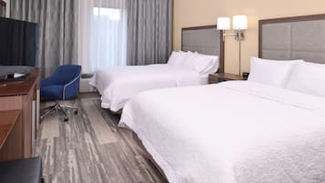 A hotel room with two beds, a desk with a computer, a chair, and a television.